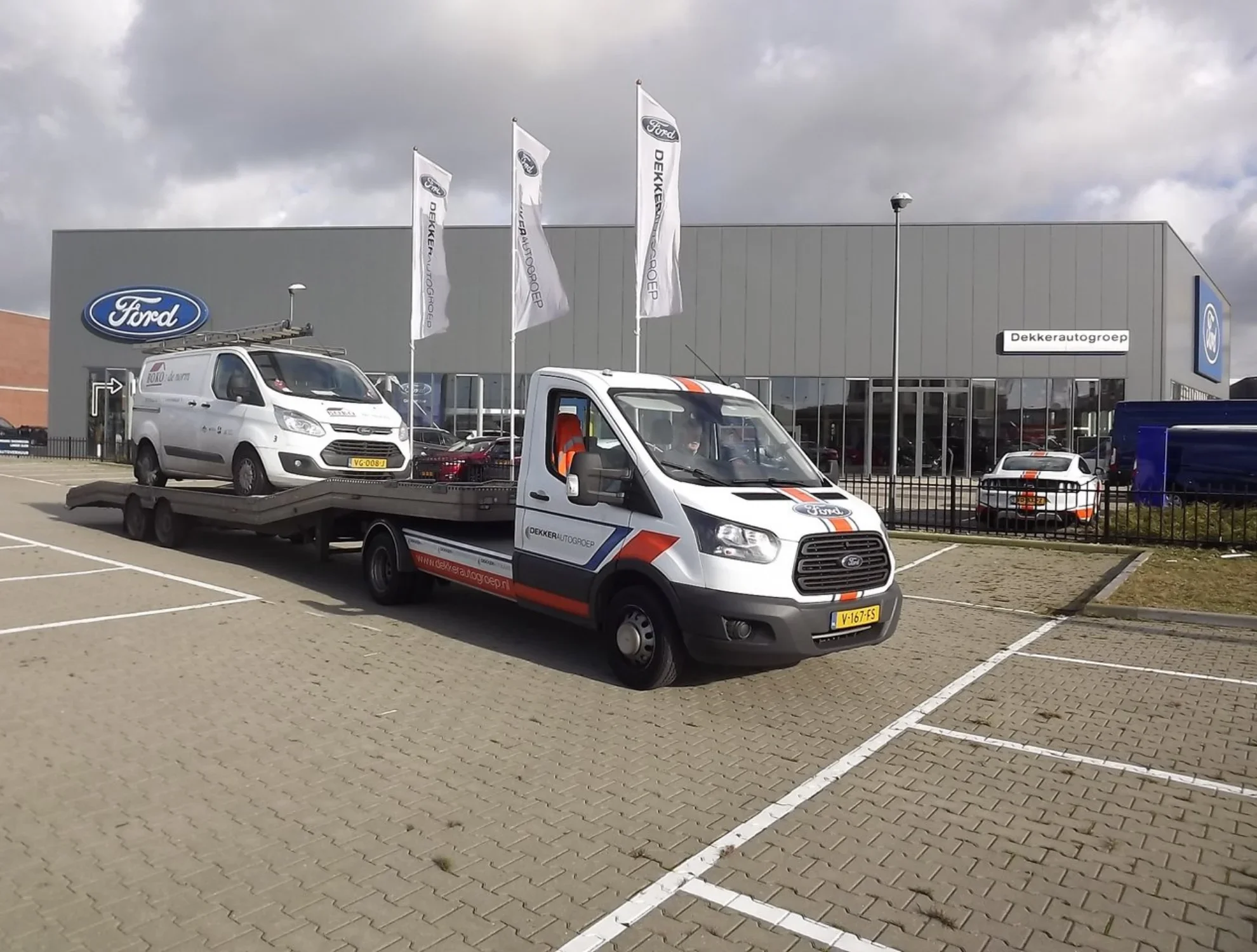 Autotransporter bij Ford-dealer — illustratie van de automotive branche waarin EVO-IT transportplanning software inzet voor efficiënte logistiek.